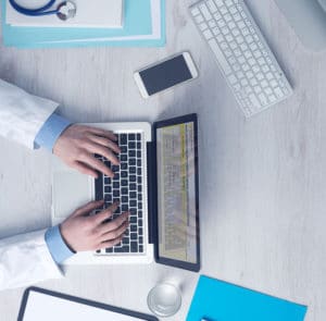 Doctor at desk with laptop and phone | TeleMed Inc.