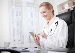 Smiling doctor looking at phone in office